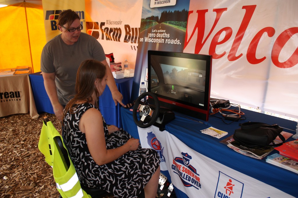 Theresa Nelson guides an operator through the simulator at Farm Tech Days 2016.