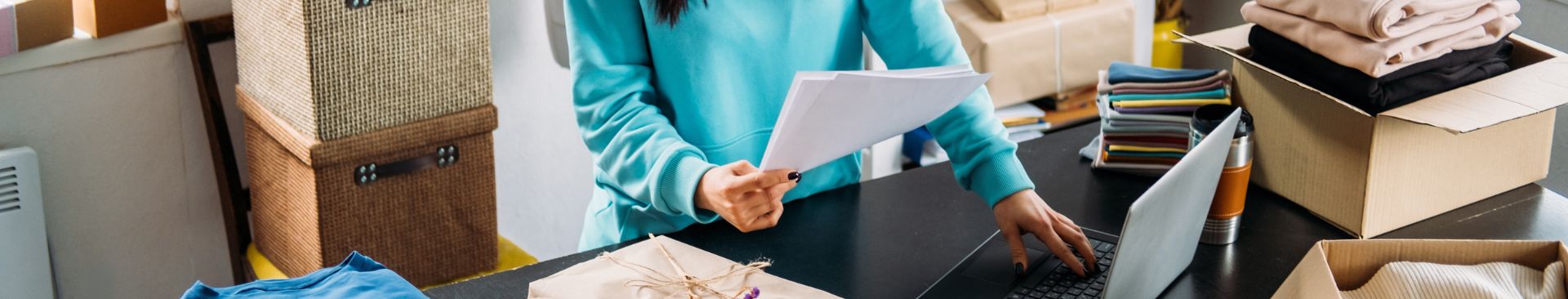 girl holding paper typing on laptop