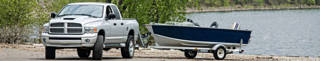 truck towing boat by lake