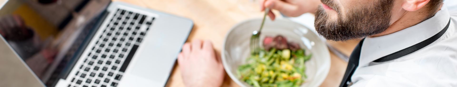 man eating salad at a desk